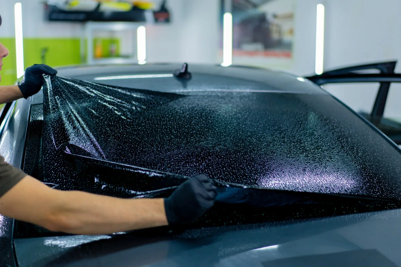 Installer fitting window film to a car rear window
