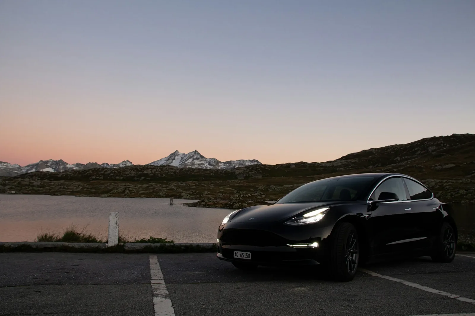 Black Tesla Model 3 beside a lake